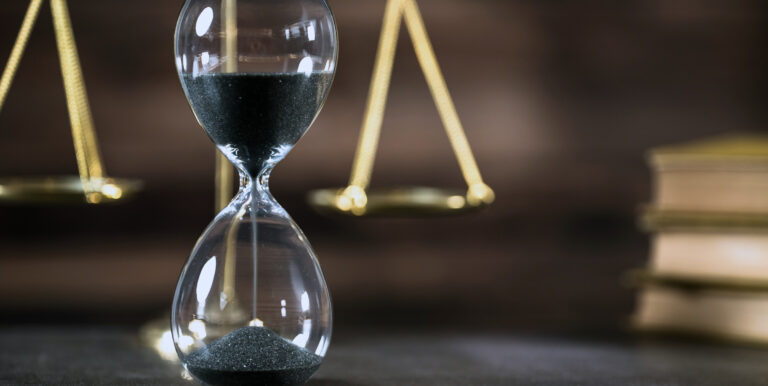 An hourglass beside the scales of justice