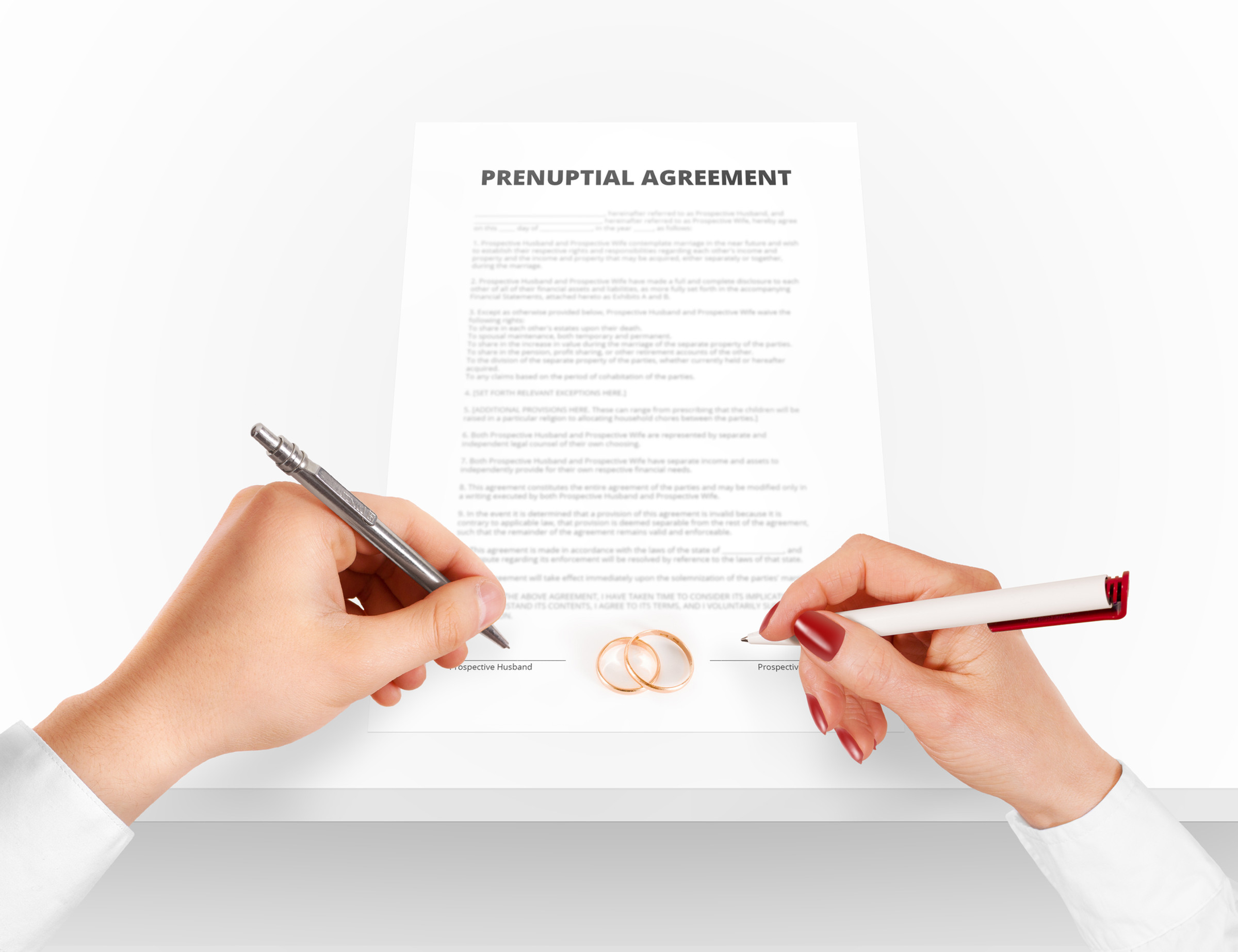 A man's hand and a woman's hand signing a prenuptial agreement, with wedding rings on the document